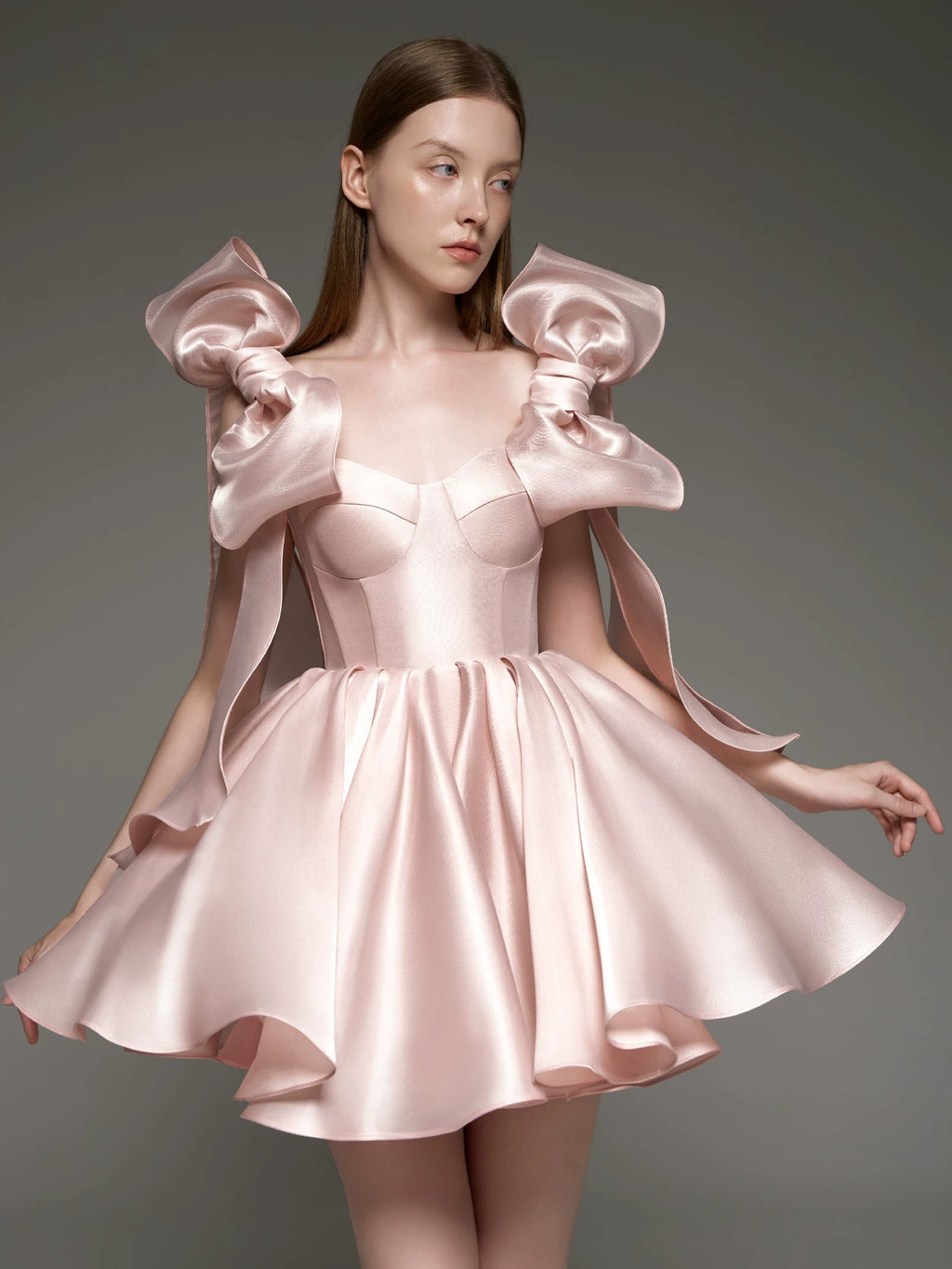A woman modeling a light pink satin formal dress with dramatic ruffled shoulder details and a flared skirt, shown against a dark gray studio background. The brand name 'Lusilk' appears at the top with Chinese characters, and 'Customized formal dress' is printed at the bottom.
